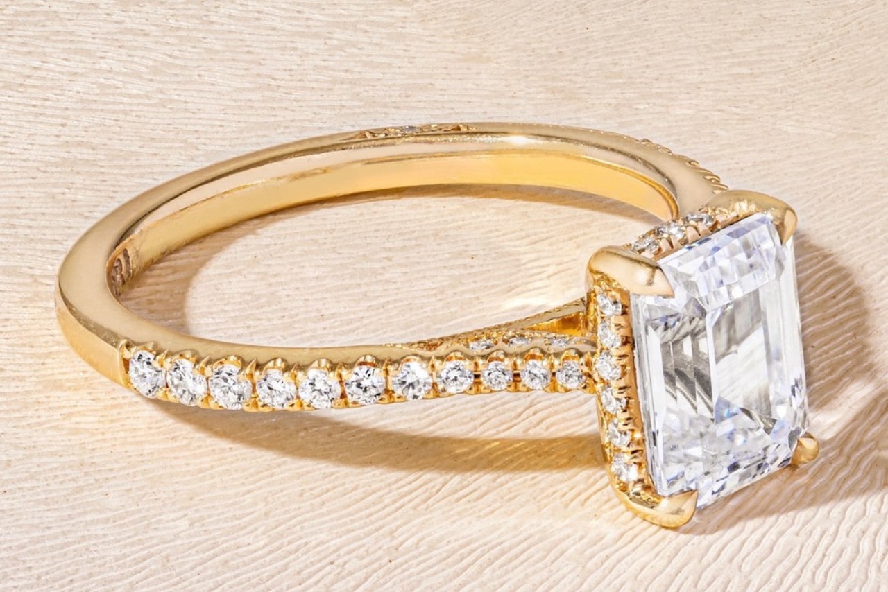 A yellow gold side stone ring by TACORI with an emerald cut center stone. 
