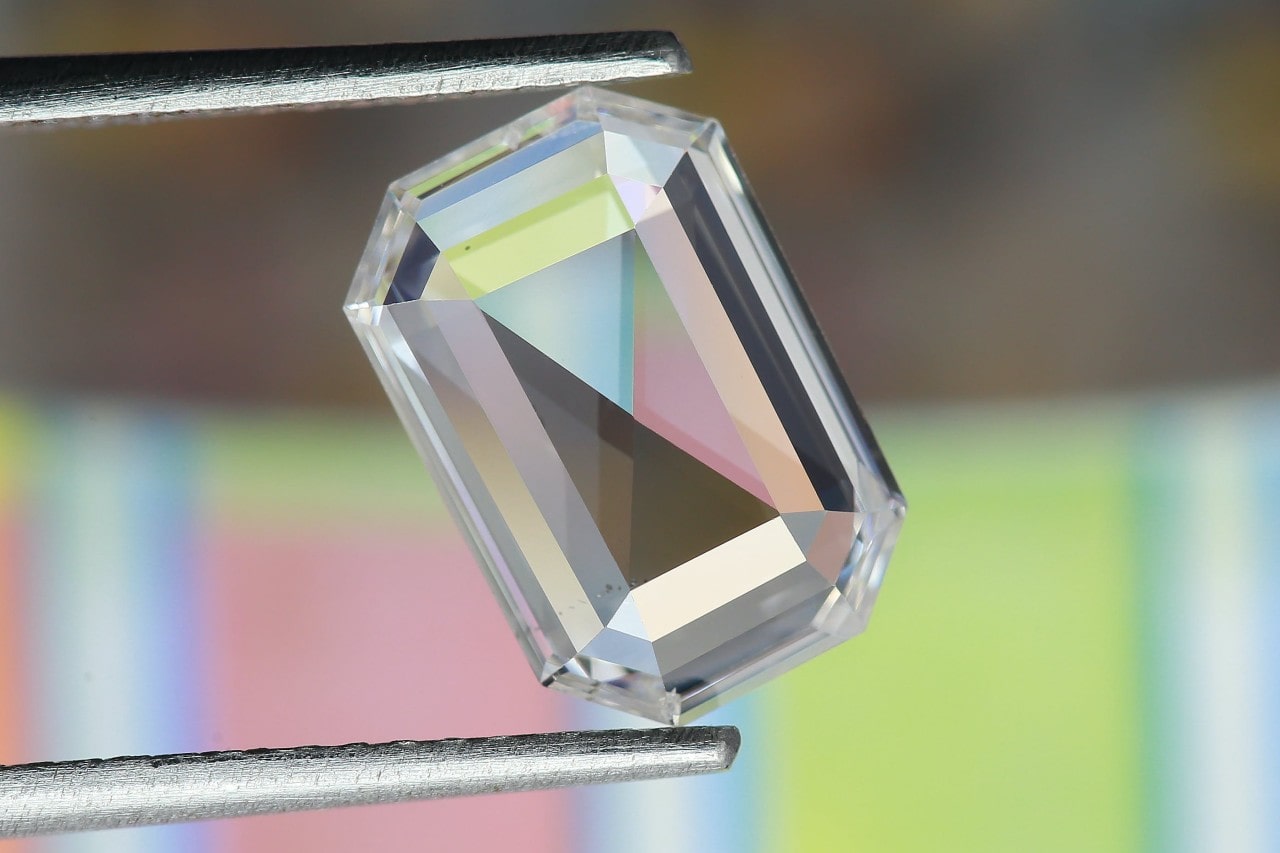 an emerald cut diamond held between tweezers
