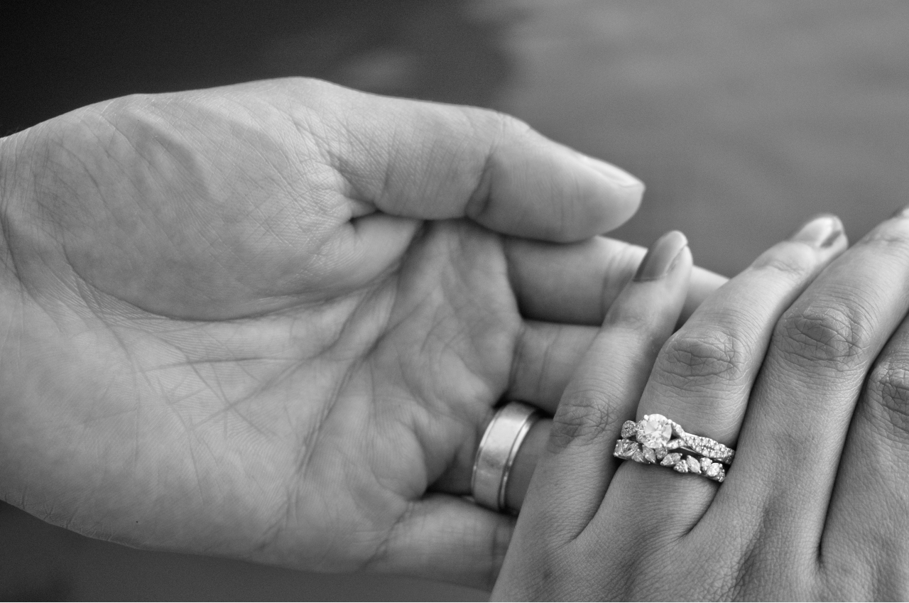 two hands clasped and wearing bridal rings