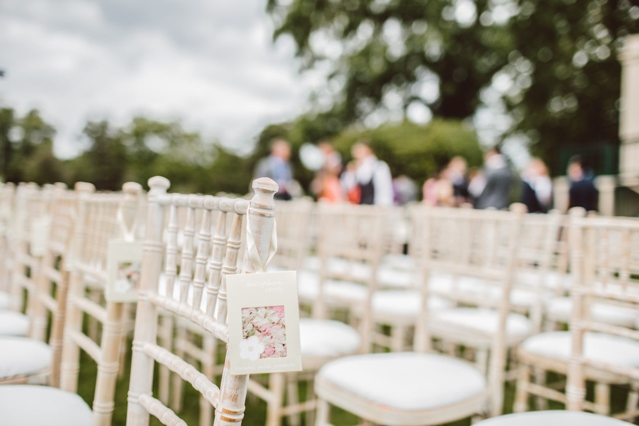 an outdoor wedding with rows of white chairs