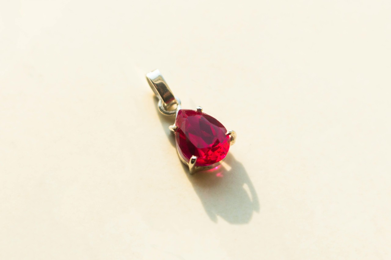 A red gemstone earrings on a beige background