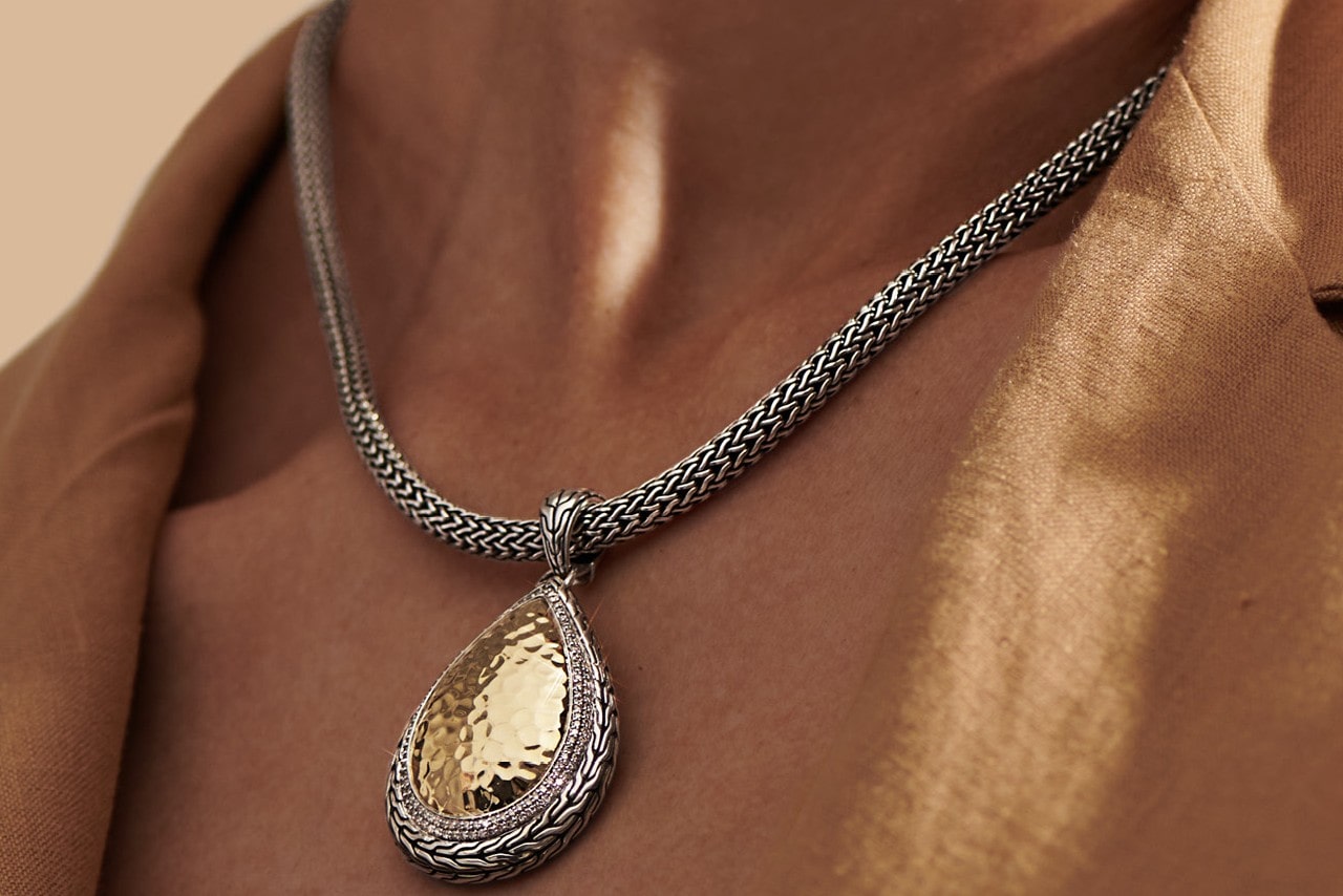 close up image of a person’s neckline wearing a chunky chain pendant necklace from John Hardy