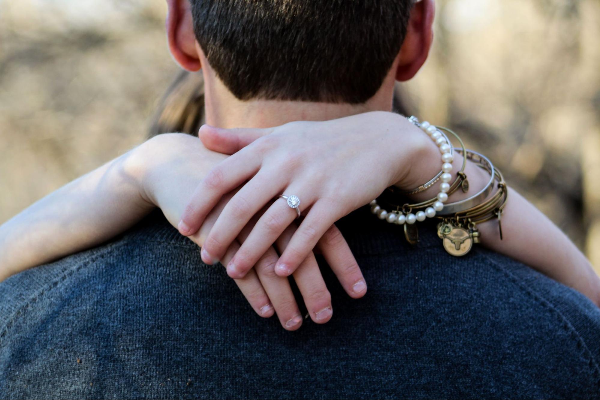 A woman embracing her fiance wears a pearl bracelet with stacks of bangles. A woman embracing her fiance wears a pearl bracelet with stacks of bangles.