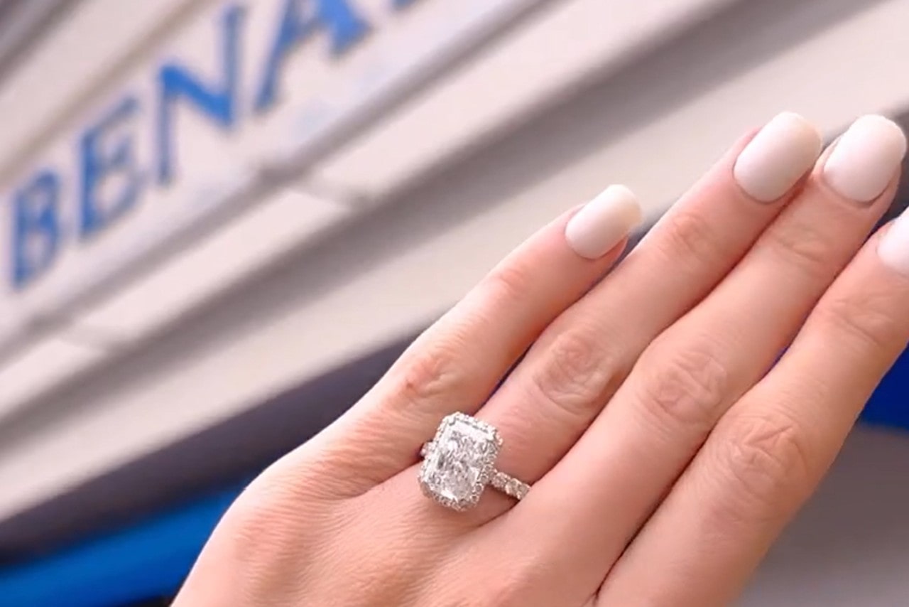 A halo ring with emerald cut center stone outside BENARI JEWELERS